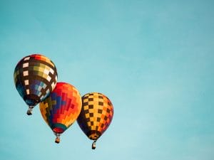 three colorful hot air balloons are flying in a blue sky