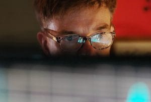 a man wearing glasses looks at a computer screen
