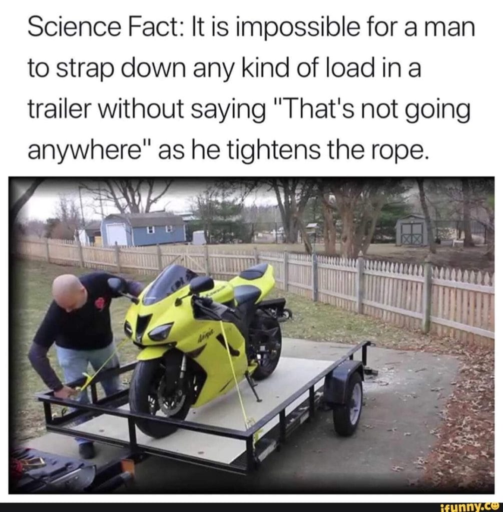 a man straps down a motorcycle on a trailer