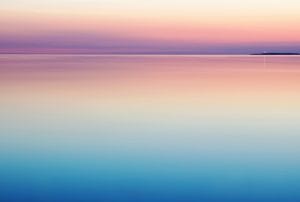 a sunset over the ocean with a small island in the distance