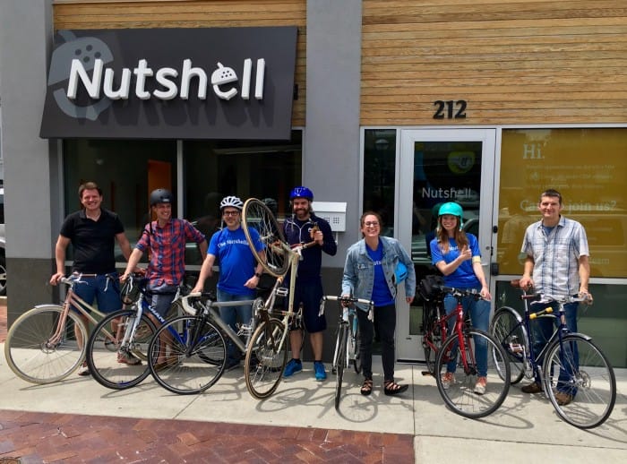 Nutshell staff members posing with bicycles standing in front of a Nutshell store