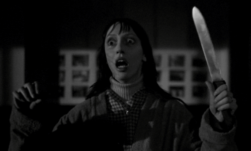 a frightened woman looking around while holding a knife