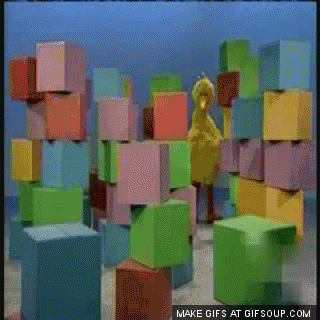 big bird is walking into and knocking over stacks of colorful blocks