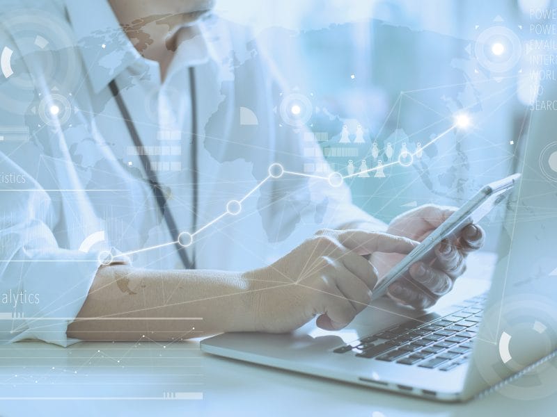 a person is using a laptop and a cell phone with a graph behind them that says analytics