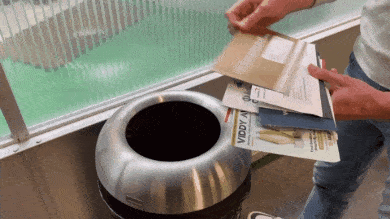 a person is putting envelopes into a trash can