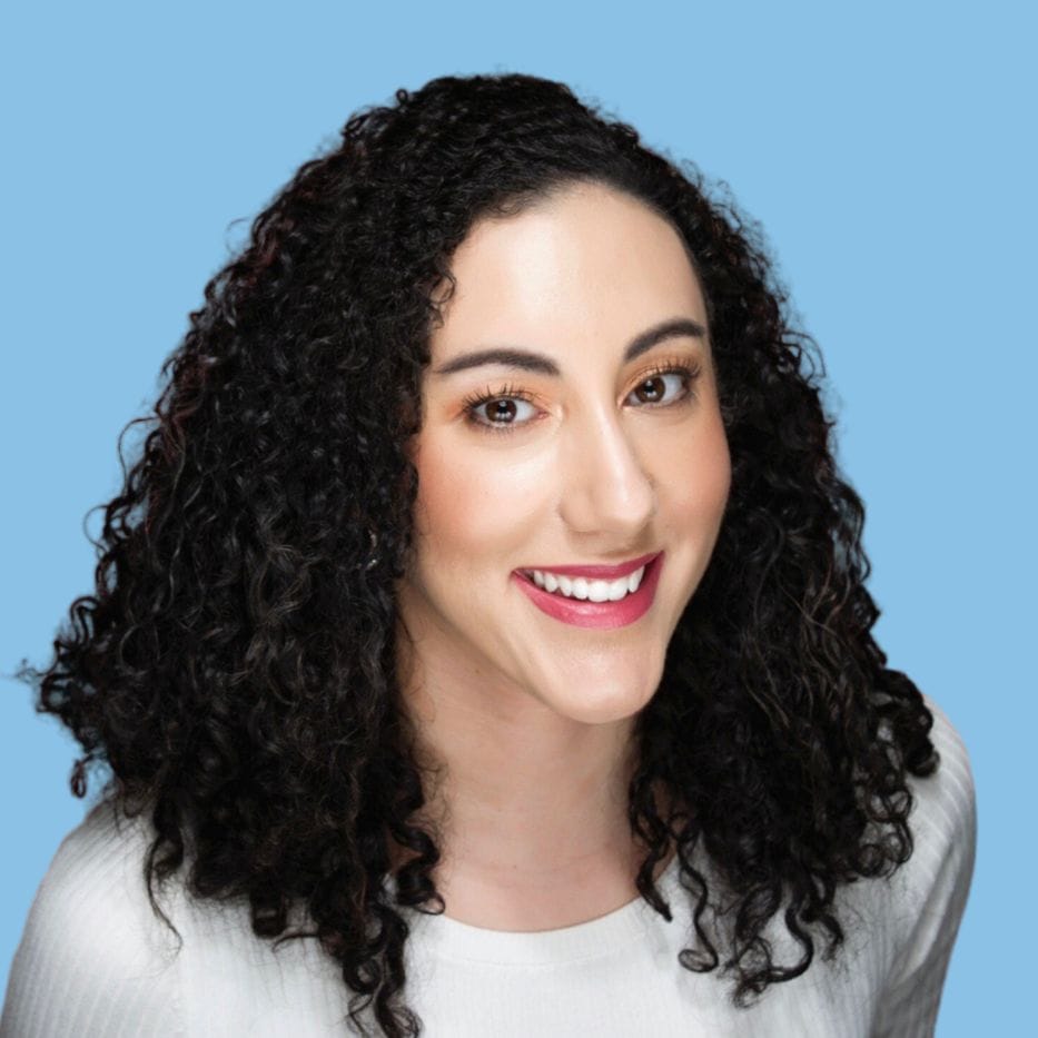 a woman with curly hair is smiling and wearing a white shirt
