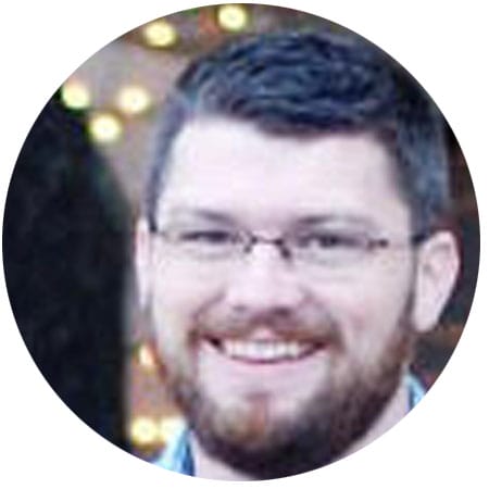 a man with a beard and glasses is smiling in a circle .