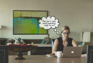 A woman sits at a table with a laptop and a thought bubble that says, "How can I make email marketing work for me?"