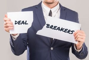 a man in a suit is ripping a piece of paper that says dealbreakers
