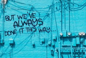 a blue brick wall with graffiti that says but we've always done it this way