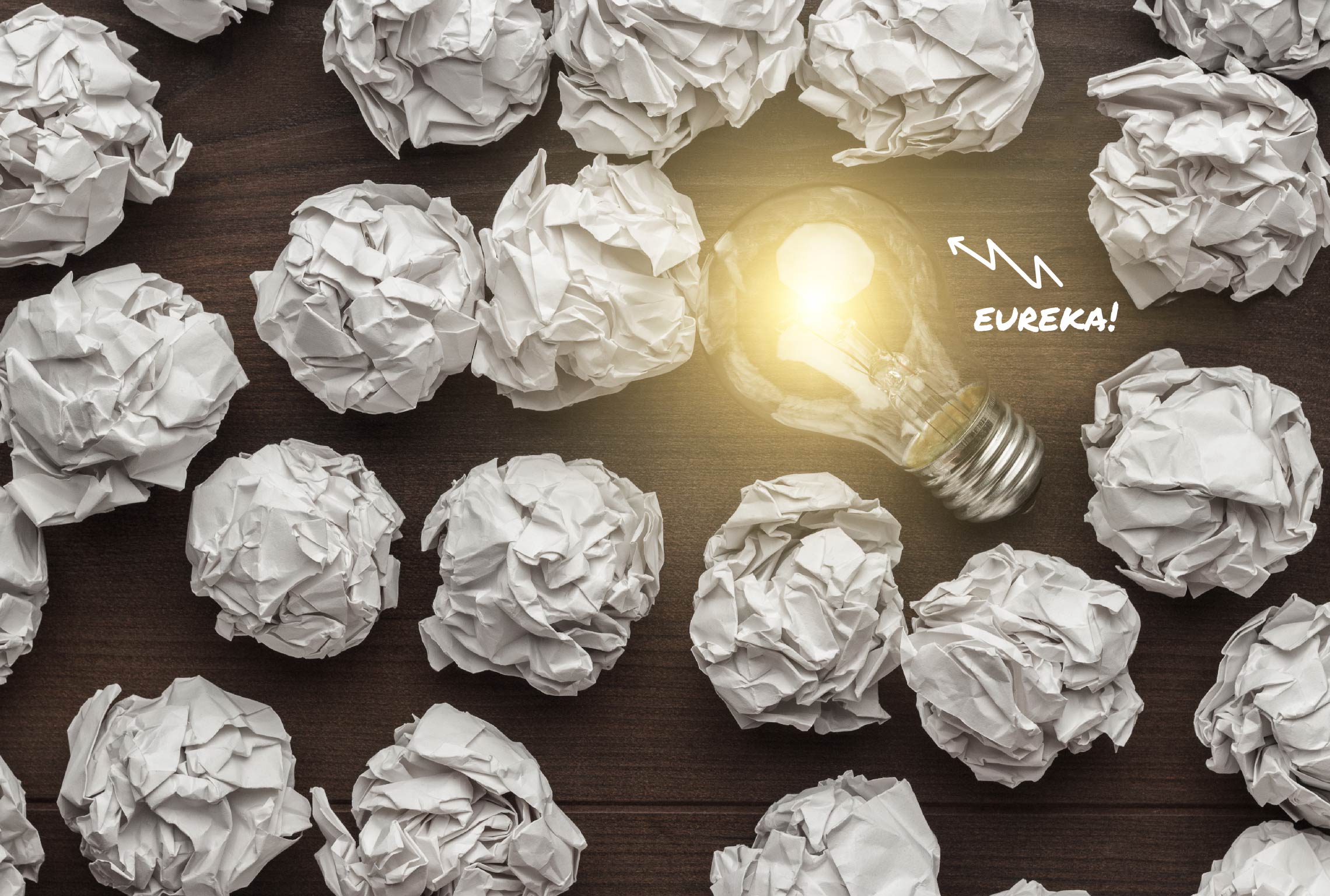 a light bulb is surrounded by crumpled paper and the word eureka is above it