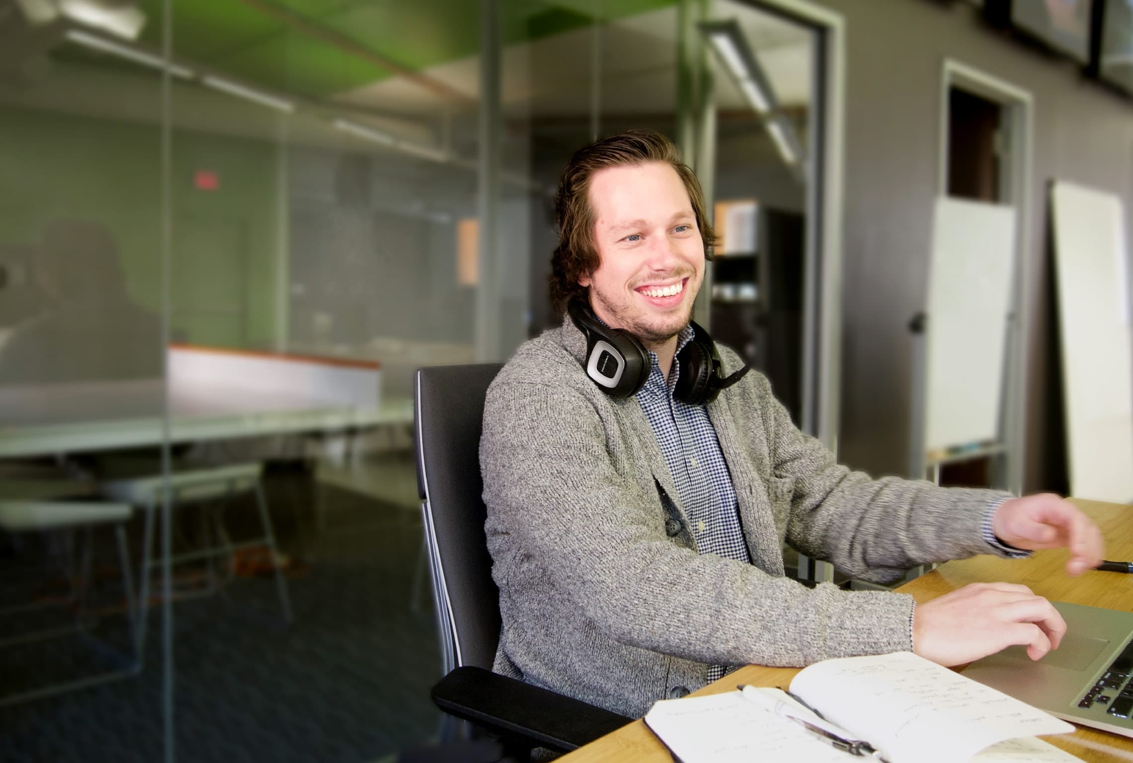 a man wearing headphones sits at a desk with a laptop