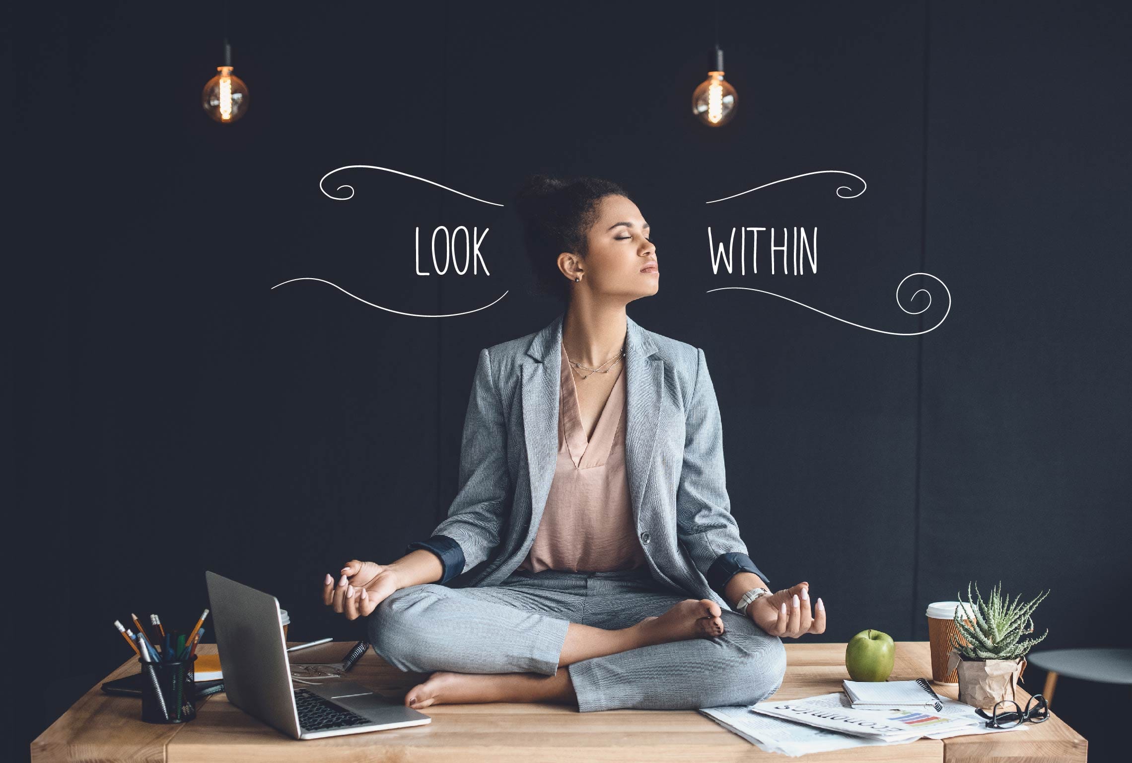 a woman sits in a lotus position on a desk with the words look within behind her