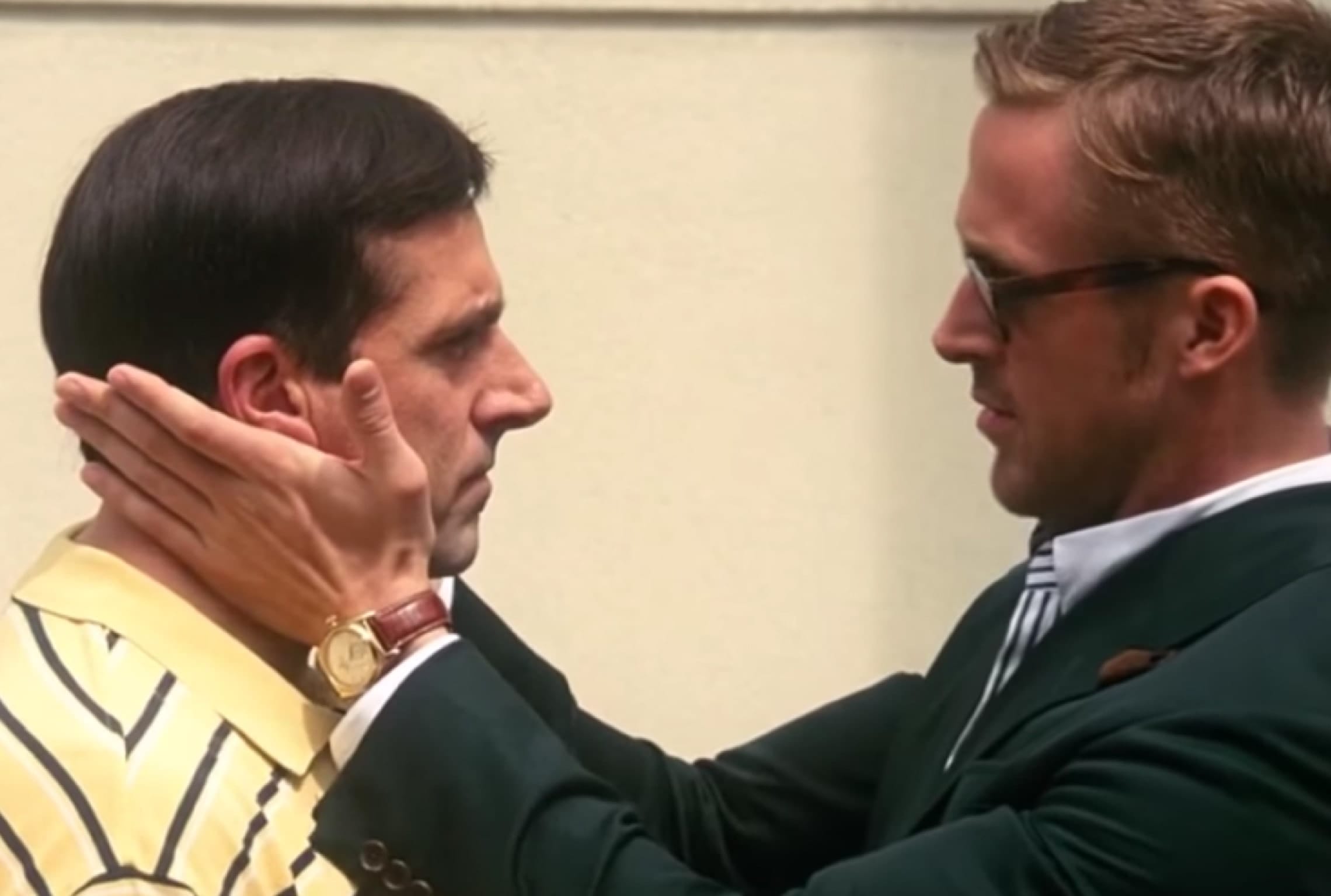 a man in a green suit touches another man's face