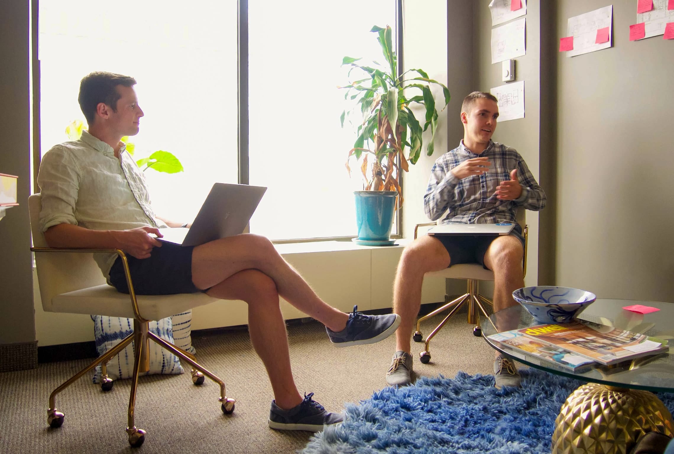 Andy Fowler en Chris Cain zitten in stoelen met hun benen gekruist met laptops