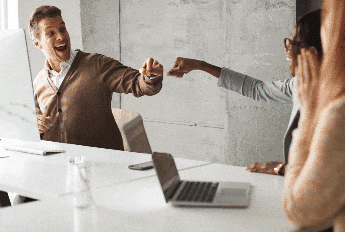 a group of people sitting around a table with a laptop