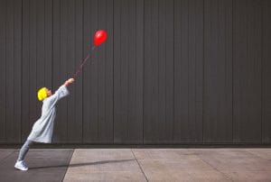 a woman in a yellow hat is holding a red balloon