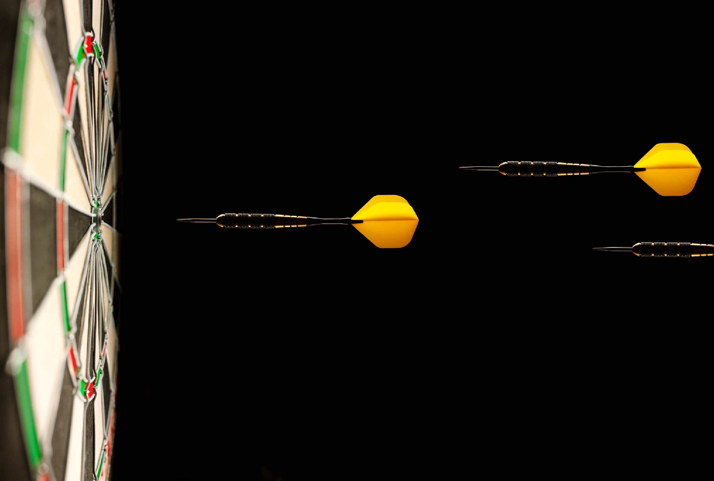 tres dardos amarillos vuelan hacia el centro de una diana