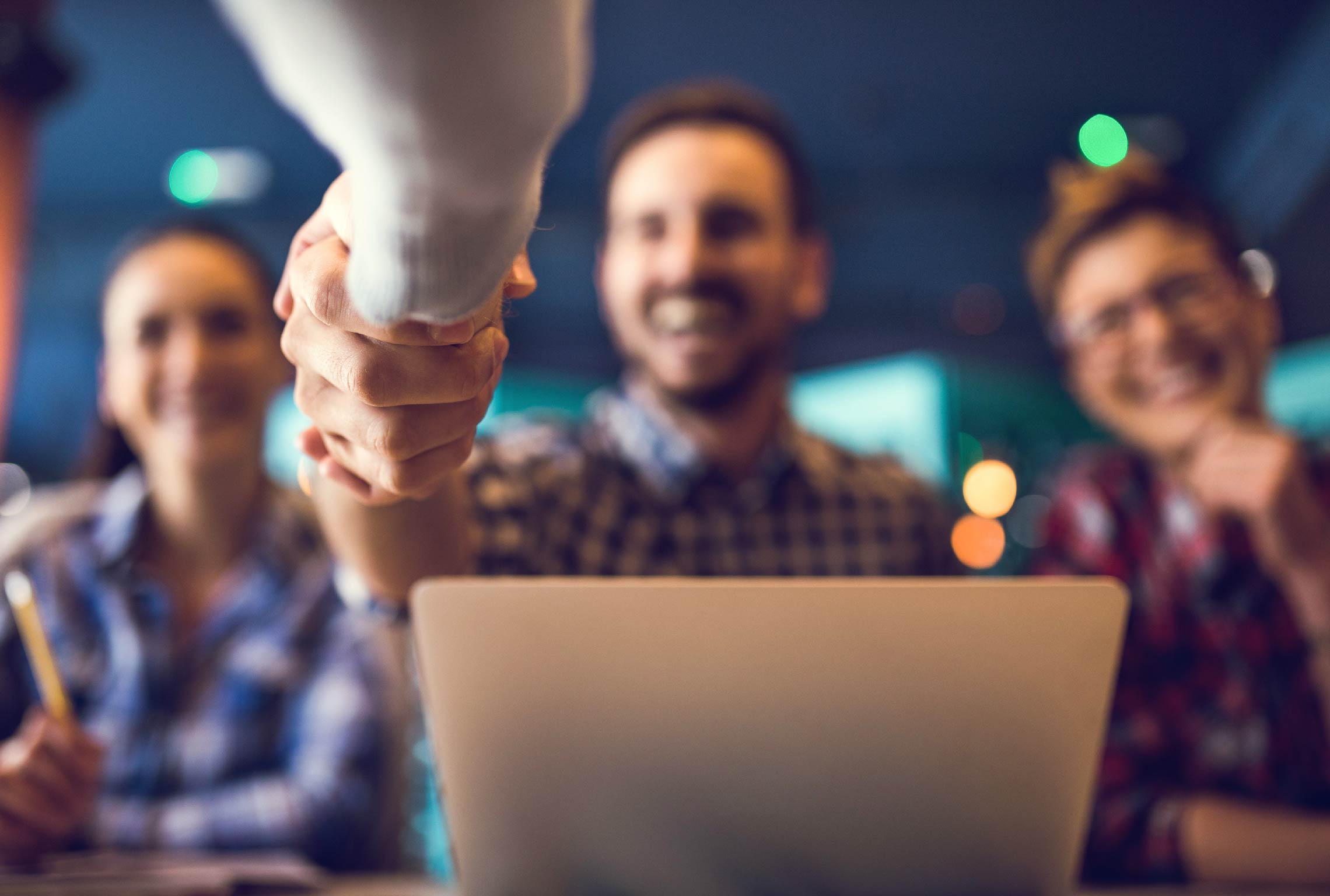 a group of people shaking hands in front of a laptop