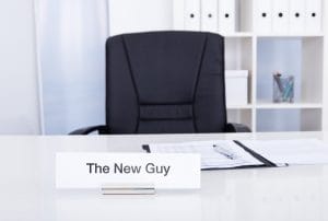 a sign on a desk that says the new guy