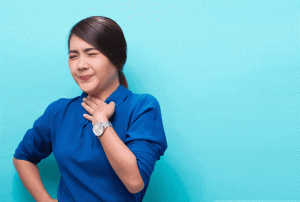 a woman in a blue shirt is holding her throat and wearing a watch