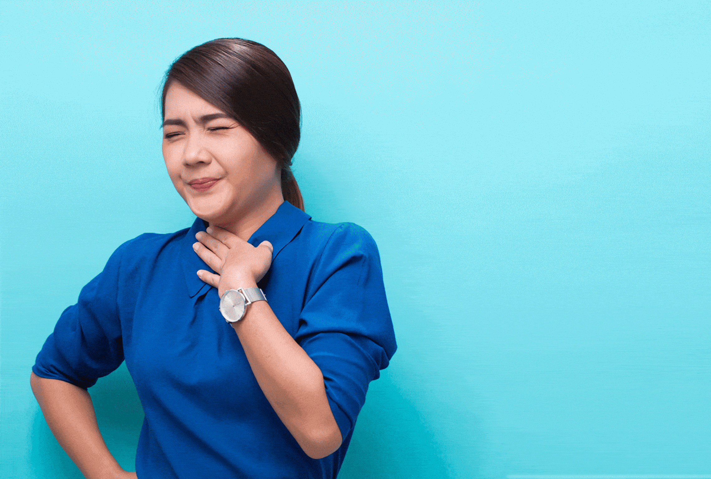uma mulher de camisa azul segura a garganta e usa um relógio
