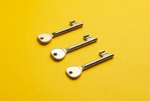 three keys are lined up on a yellow surface