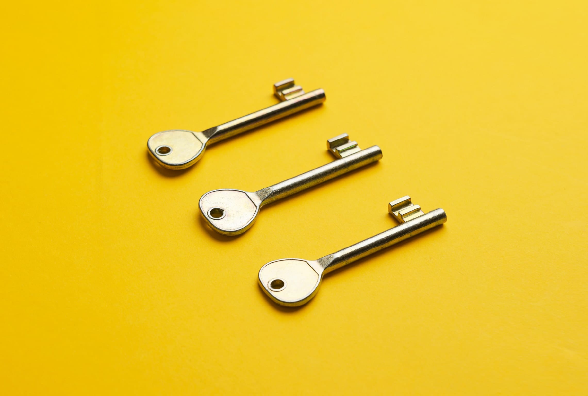 three keys are lined up on a yellow surface