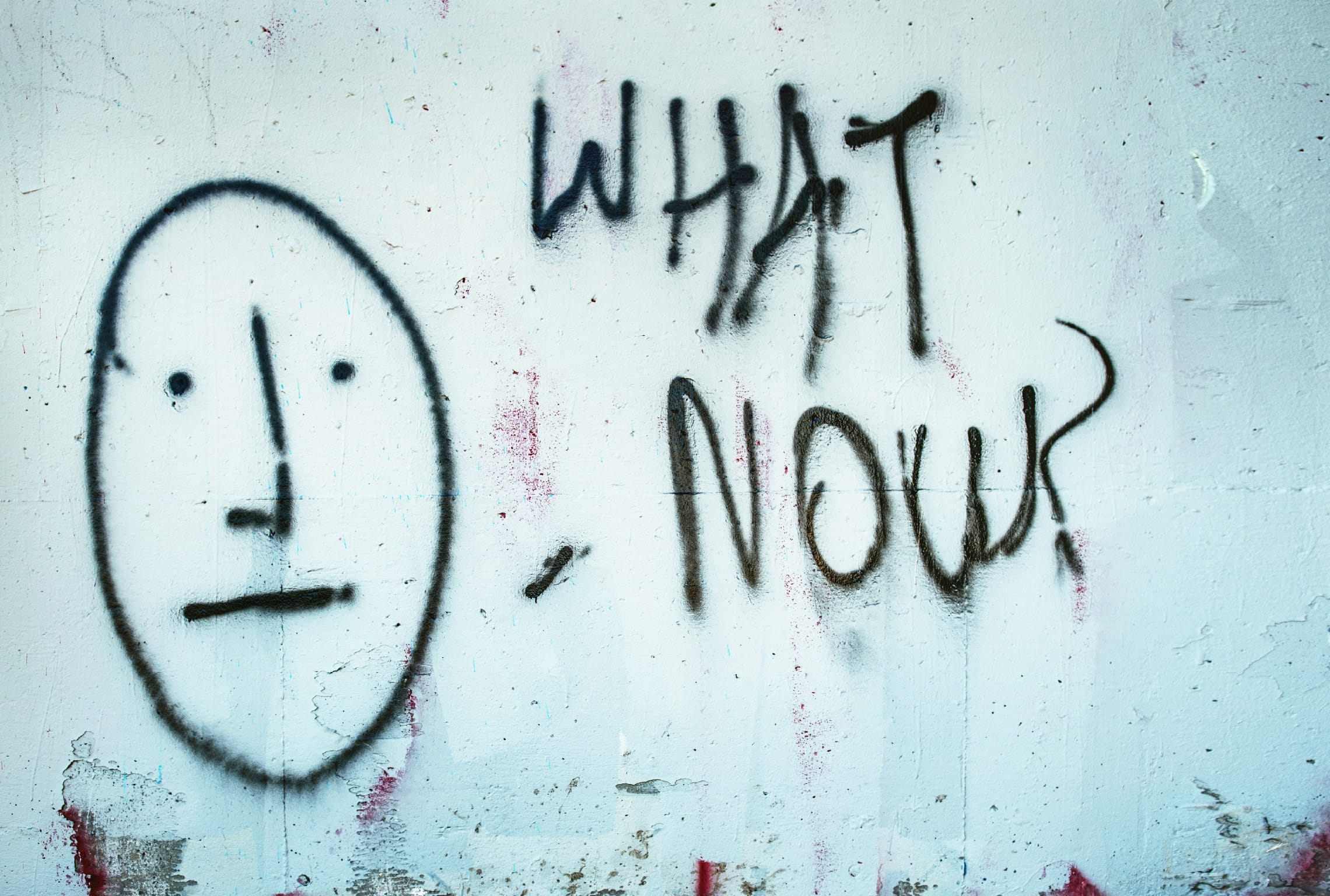 graffiti on a wall that says what now