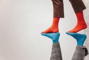 a person wearing red socks stands on top of a reflection wearing blue socks