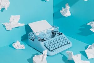 a blue typewriter is surrounded by crumpled paper