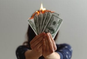 a woman hold bills of money that are burning