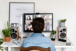 a man sits at a desk looking at a computer screen with a group of people on it