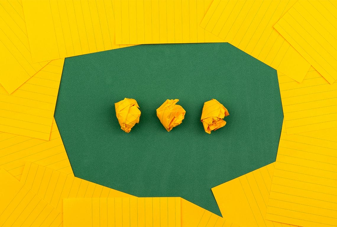 a green speech bubble with three yellow crumpled pieces of paper inside of it