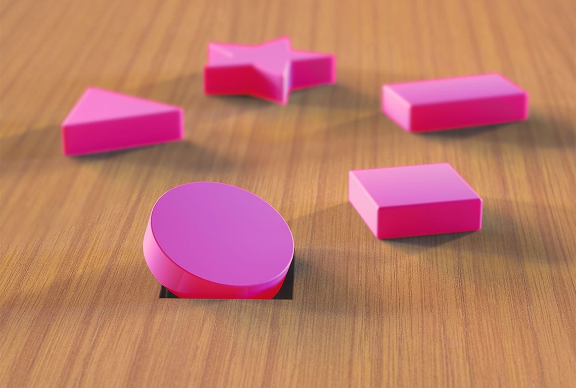 pink geometric shapes on a wooden surface with a circle stuck in a square hole