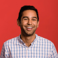 a person in a plaid shirt is smiling in front of a red background