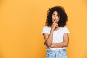 a woman in a white shirt and blue jeans is thinking