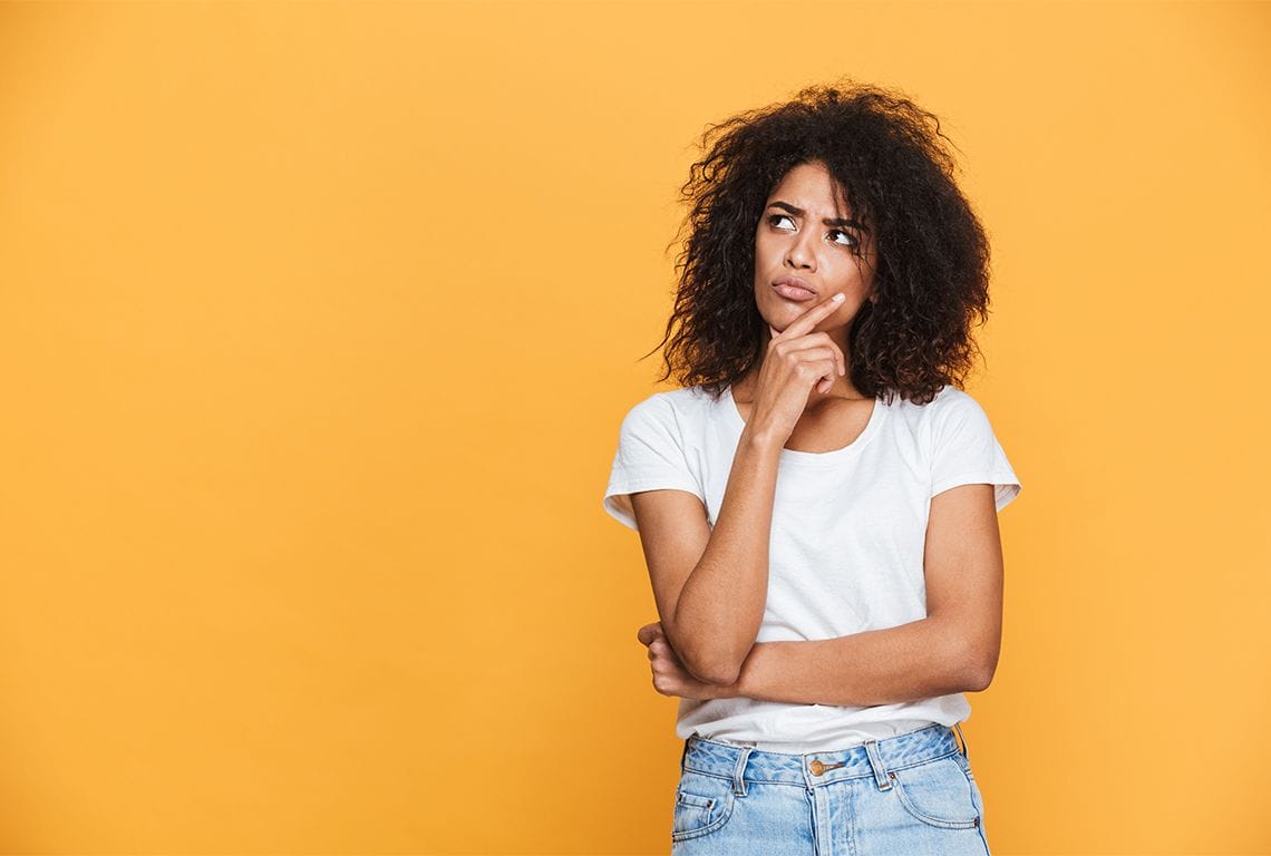 En kvinne i hvit skjorte og blå jeans tenker