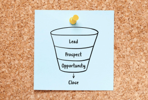a drawing of a sales funnel is pinned to a cork board