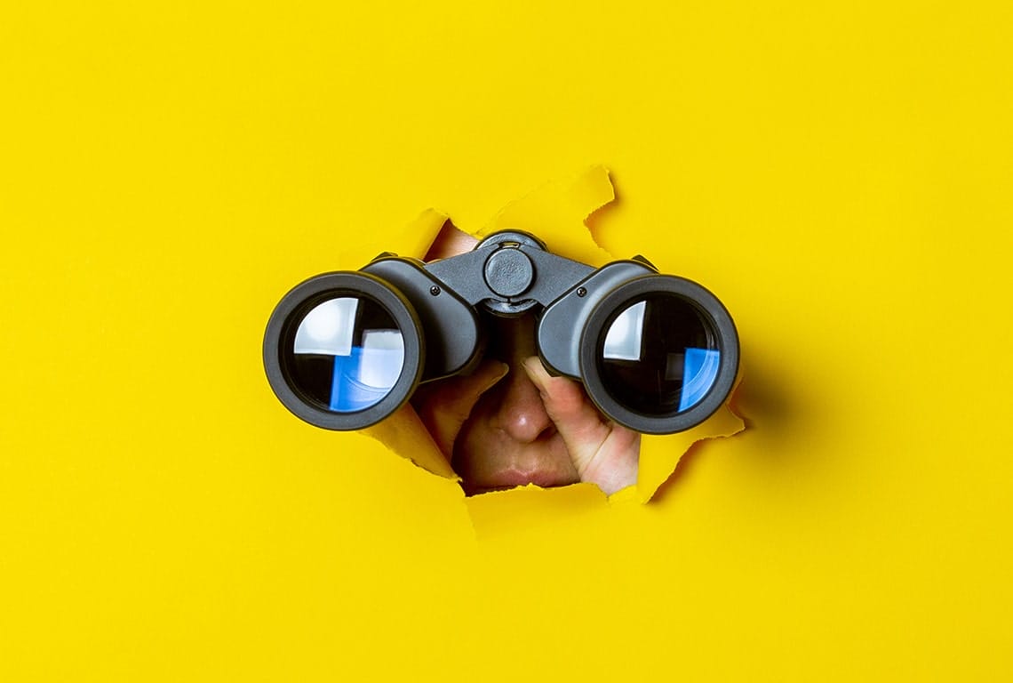 a person looking through binoculars with a yellow background