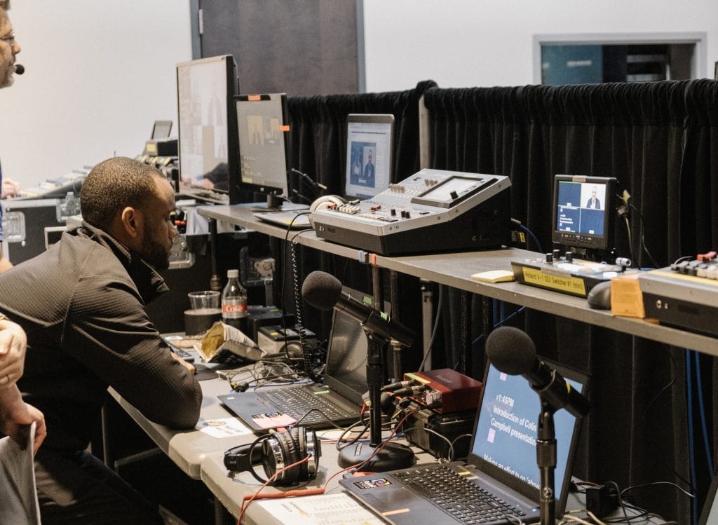 a man sits at a video control panel for the boundless conference
