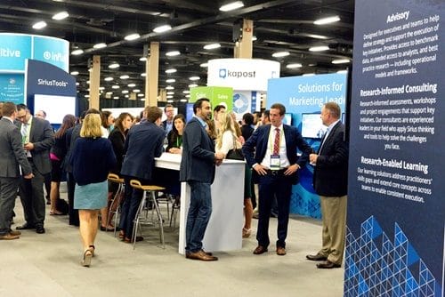 a group of people are standing around a booth at athe sirius decision 2020 summit