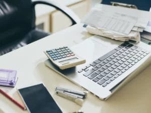 a calculator sits on a desk next to a laptop