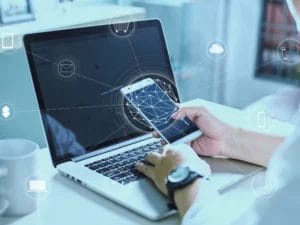 a person is using a laptop and holding a cell phone