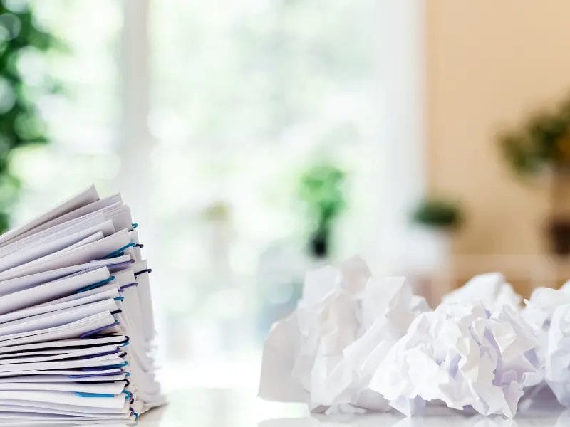a stack of papers is sitting on a table next to a pile of crumpled paper .