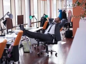 a man sits back in an office chair with his feet up on the desk