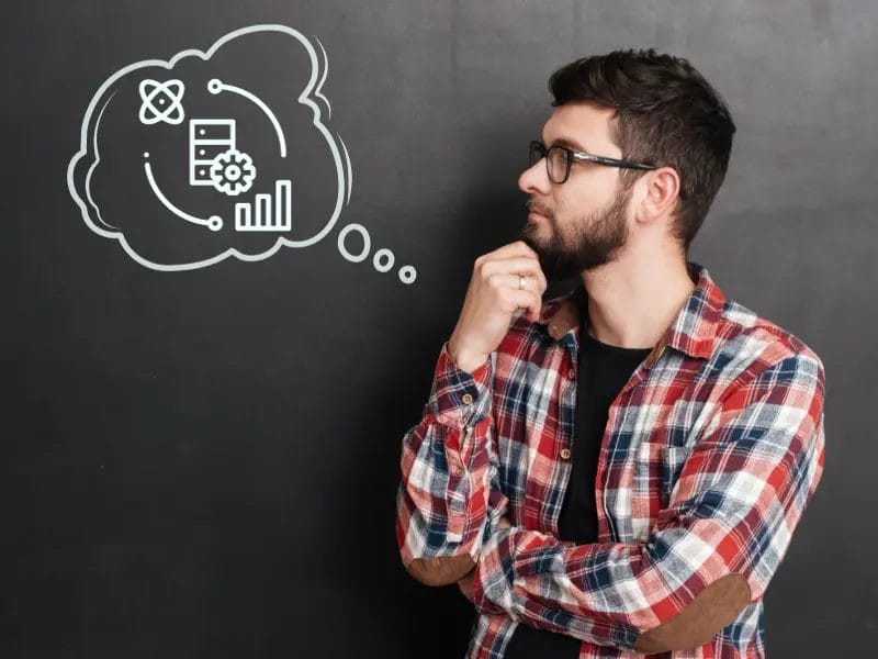 ruudulliseen paitaan pukeutunut mies seisoo taulun edessä, johon on piirretty ajatuskupla.