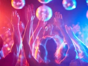 a crowd of people raising their hands in the air at a party