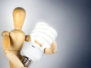 a wooden mannequin is holding a light bulb