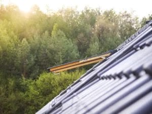 the sun is shining through the roof of a house with trees in the background .